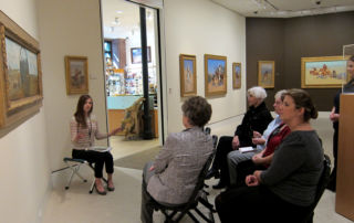 woman talking with group of adults in front of a painting