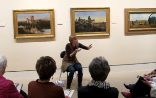 a woman talking passionately about a subject to a group of adults in a museum gallery