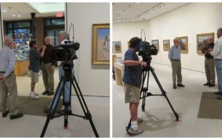 two men being filmed discussing paintings in museum gallery