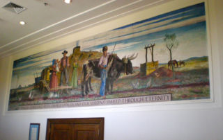 painting above wood door of pioneer family standing in front of sod house