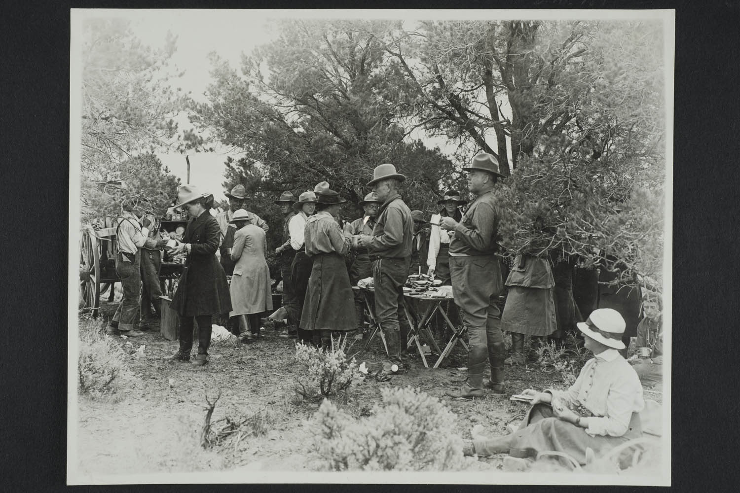 black & white photograph of men and women eating outdoors
