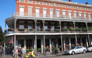 three story brick building with wrought-iron trellises on balconies