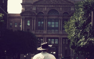 back of man driving horse-dawn wagon toward Fort Worth historic courthouse
