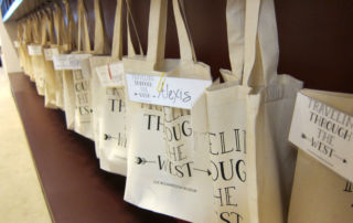 a row of canvas bags with names pinned to them