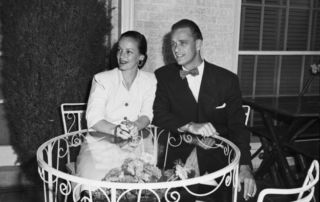 a handsome young man and woman sitting at an outdoor table