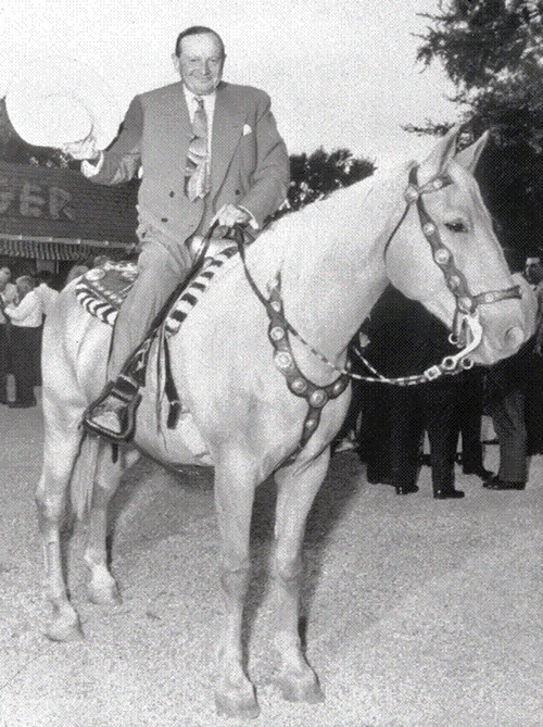 man in a suit mounted on a white horse