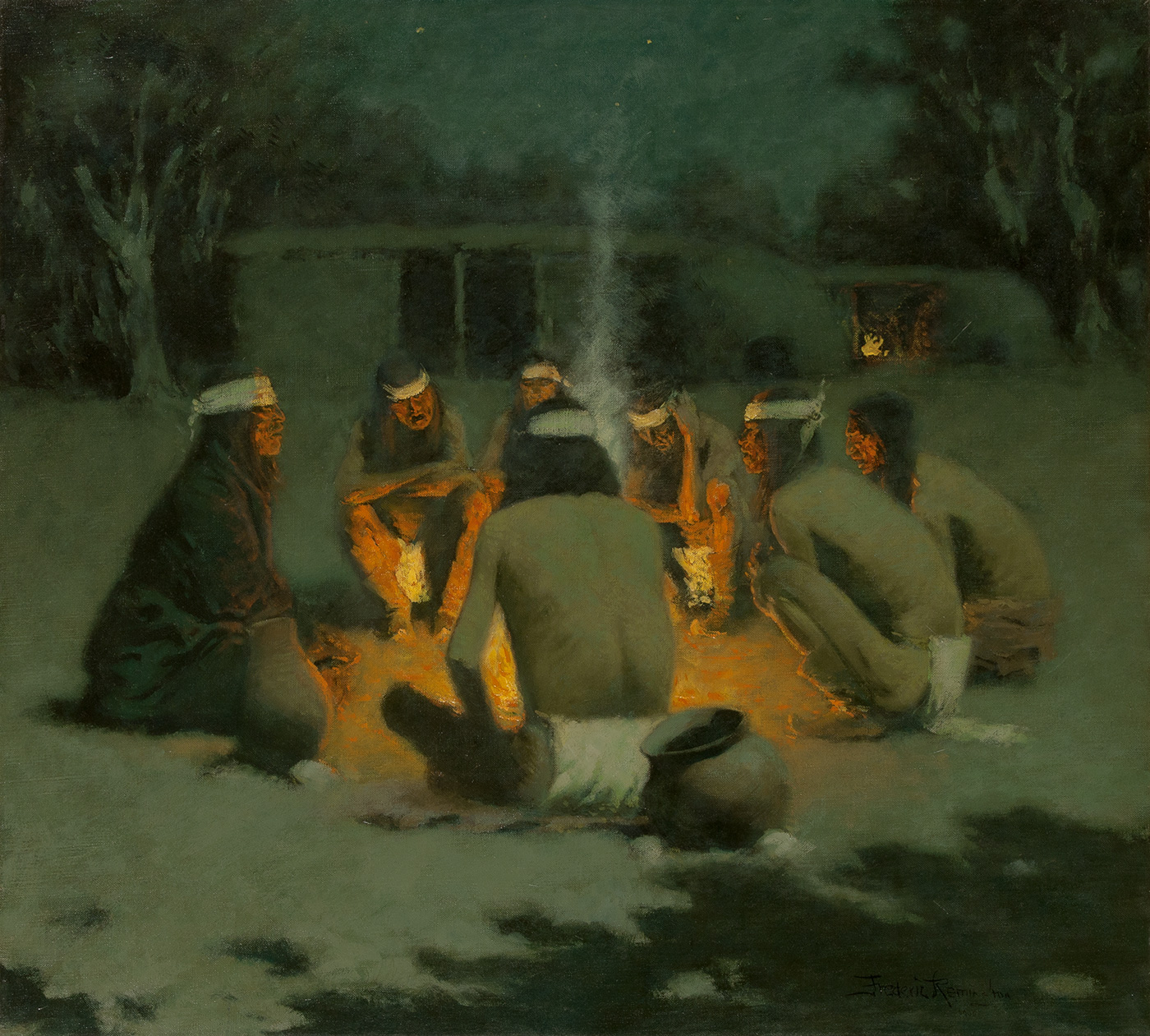 A group of Apache Indians gather closely around a campfire at night.