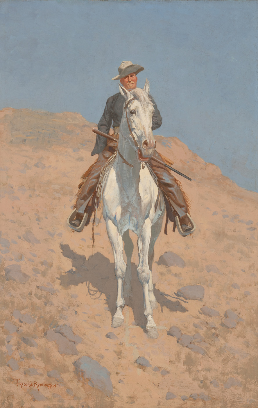 An Anglo man sits on a white horse in a rocky, barren landscape under a blue sky.