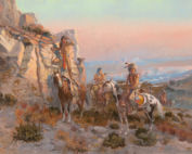 A small group of indigenous American men on horseback are stopped near a rocky outcrop looking out into the distance.