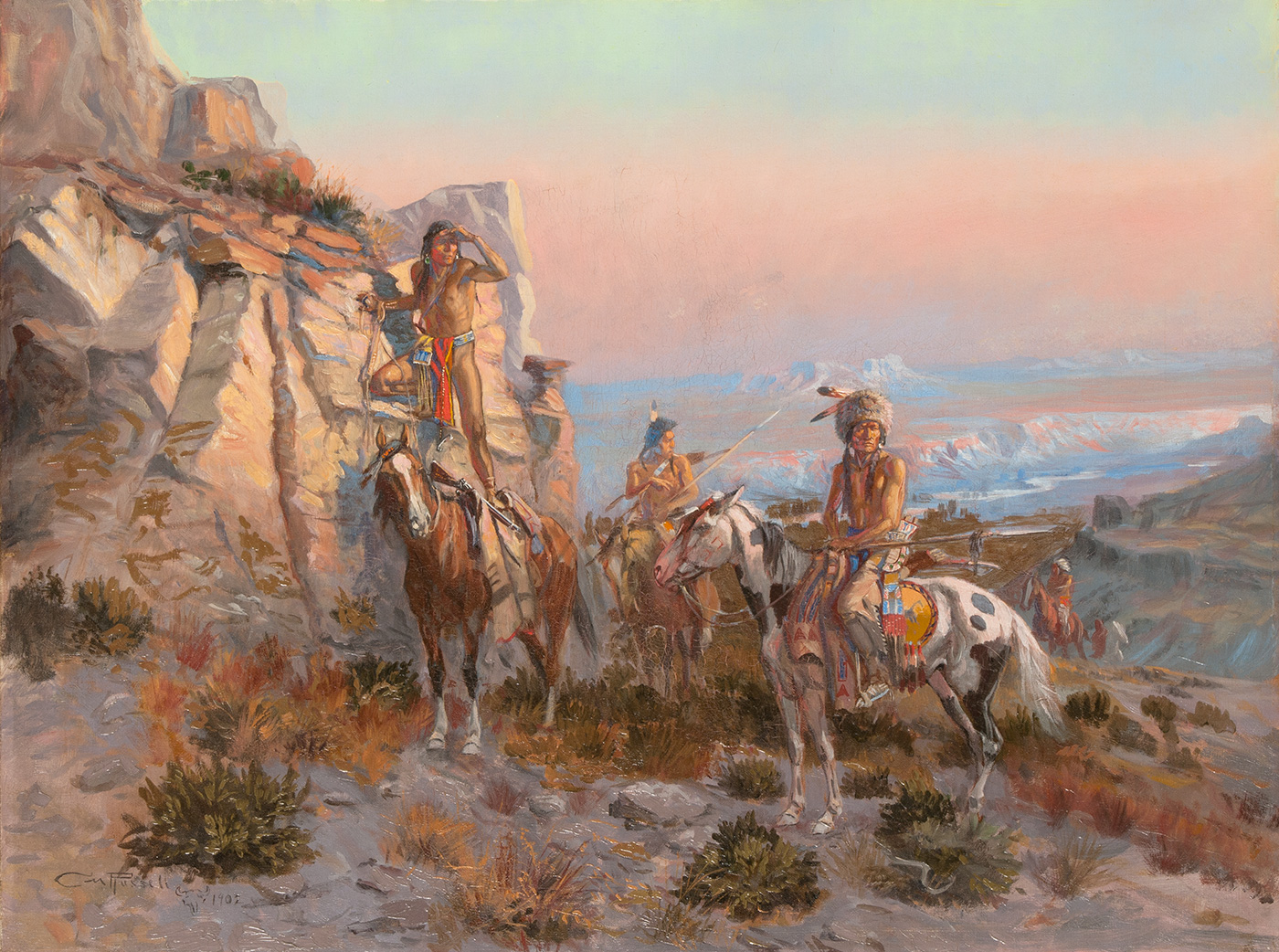 A small group of indigenous American men on horseback are stopped near a rocky outcrop looking out into the distance.