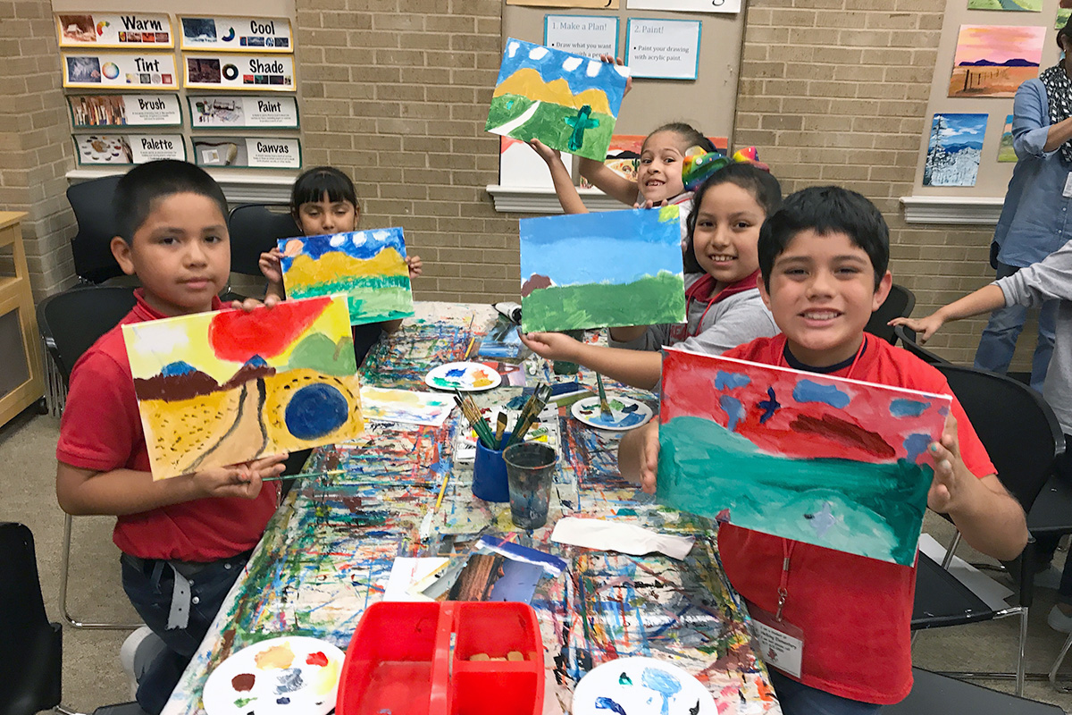 students holding their landscape paintings