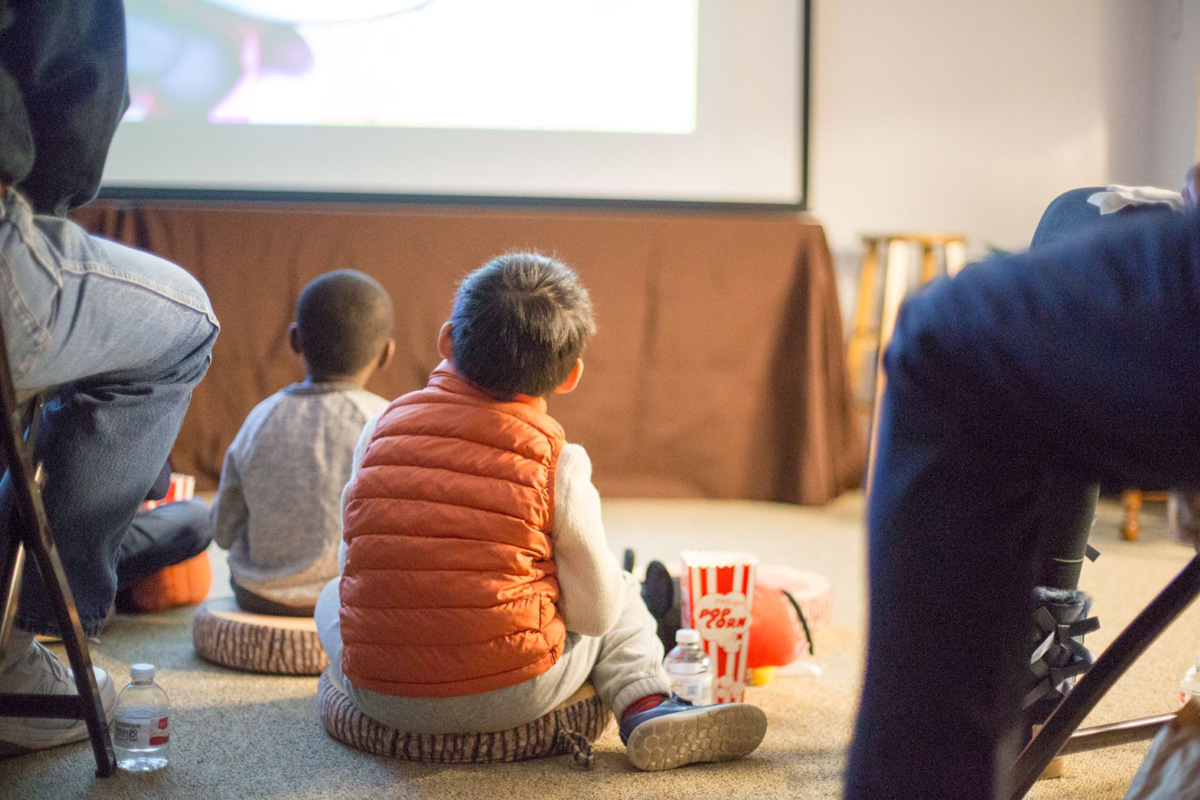 a group of little boys sitting on floor watching a movie