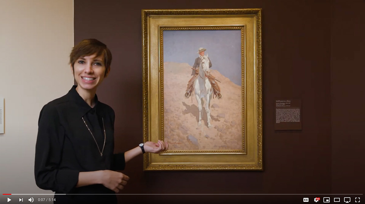 A woman pointing to a painting behind her