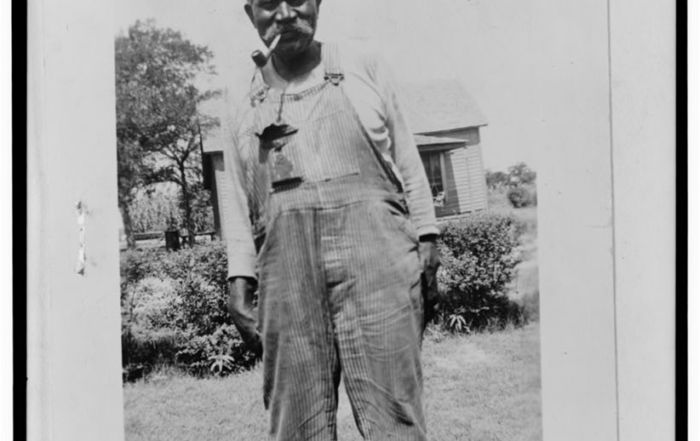 Black & white photograph of a Black man in overalls.