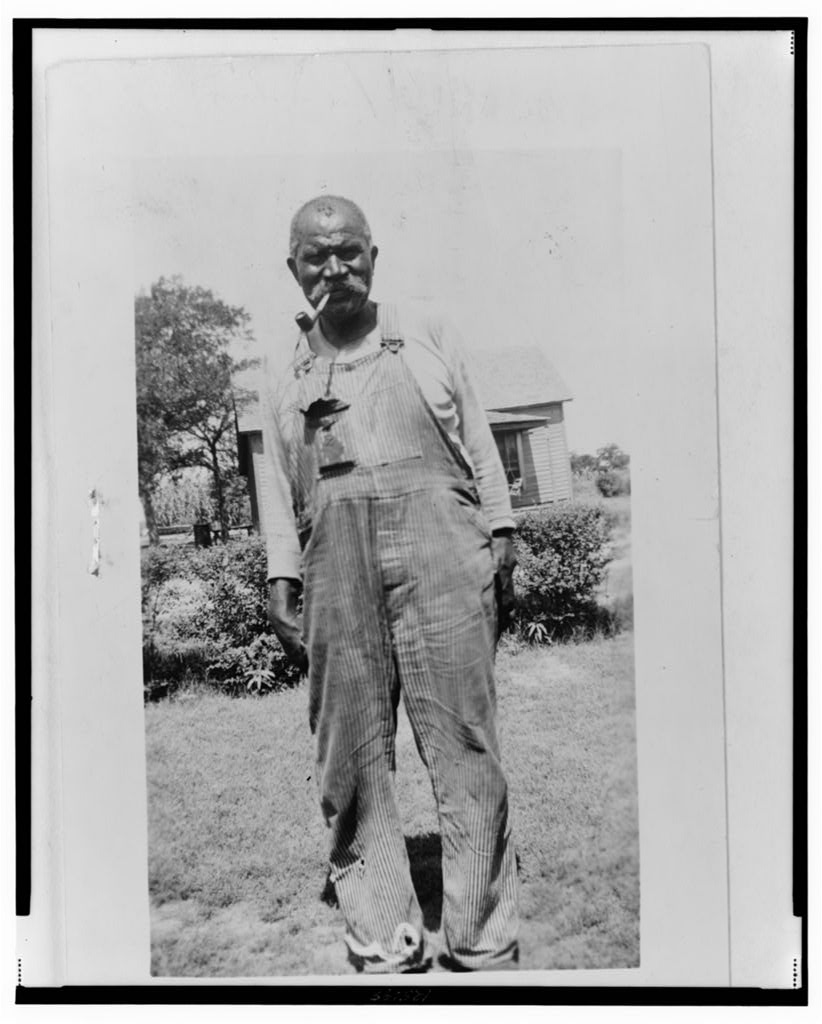 Black & white photograph of a Black man in overalls.