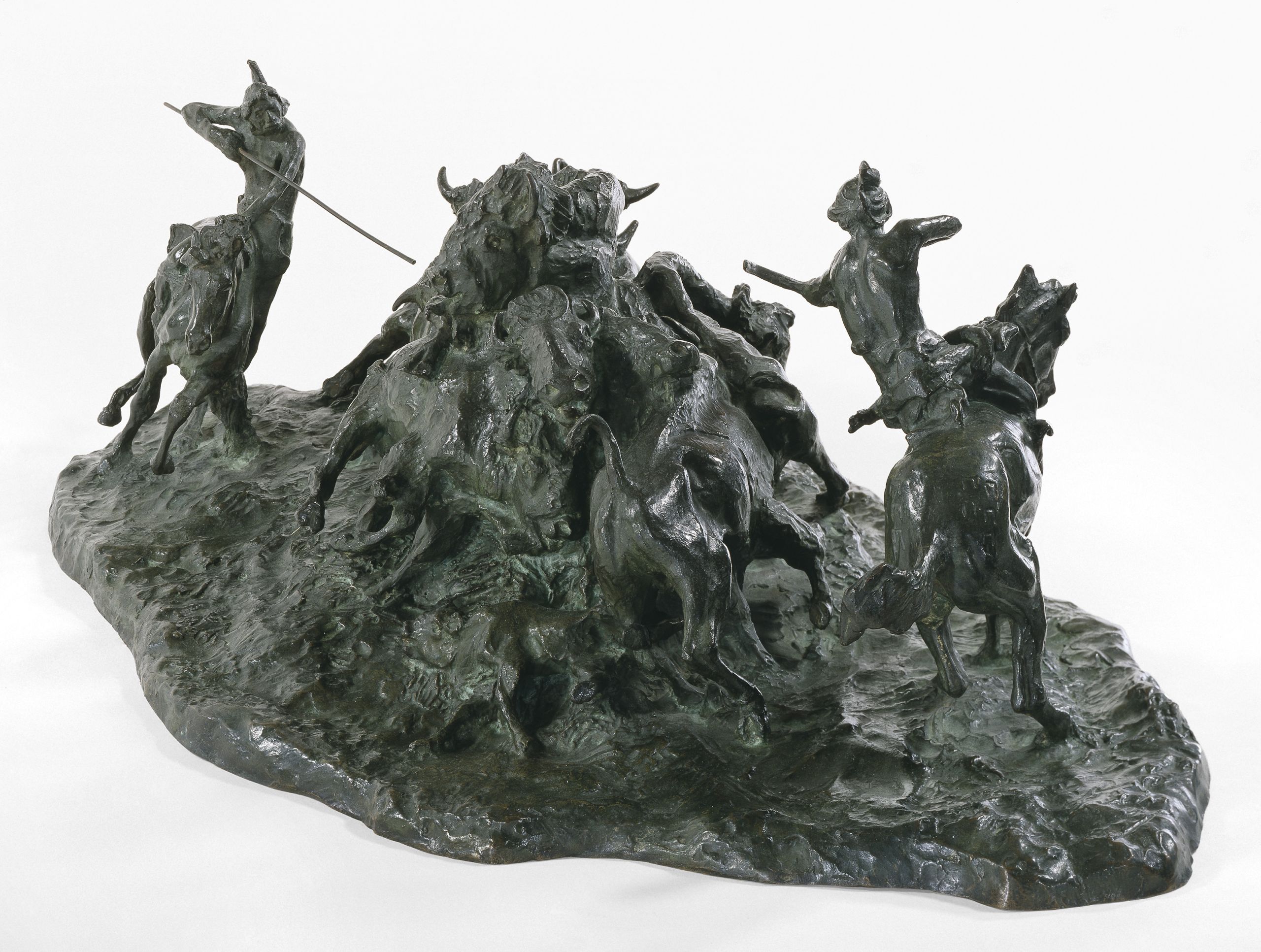 bronze sculpture of two Indigenous hunters on horseback circling a group of bison