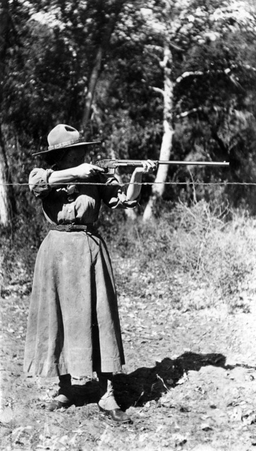 black & white photograph of a woman shooting a rifle