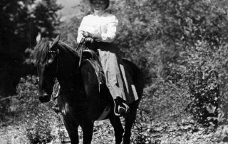 Black & white photograph of a white woman on a horse
