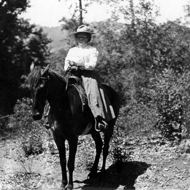 Black & white photograph of a white woman on a horse