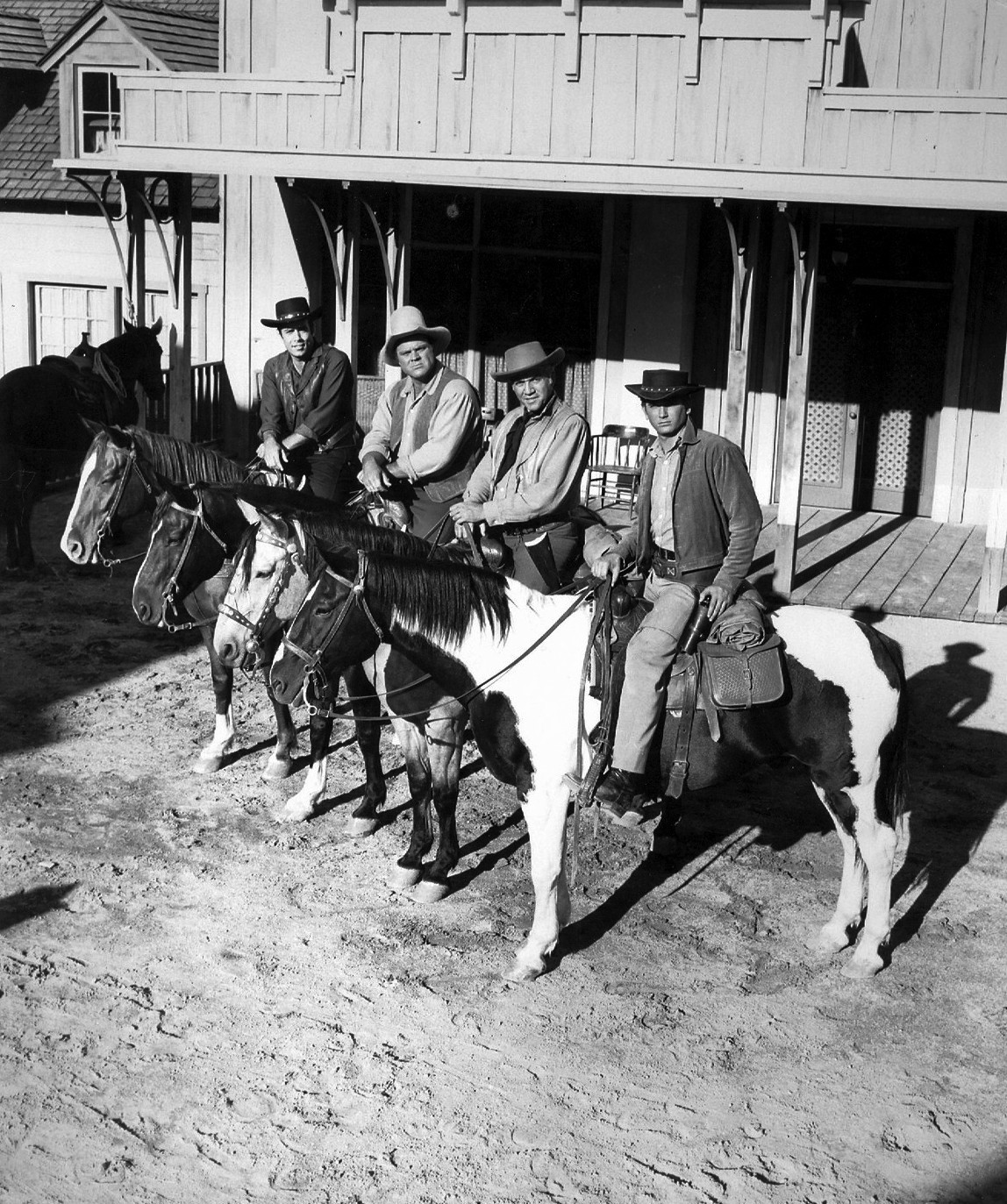 A black and white photograph of men mounted on horses in front of a building