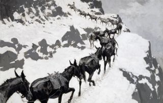 A line of pack mules hiking up a snow-covered mountain cliff.