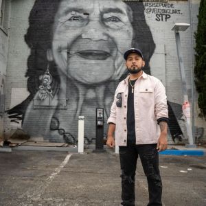 man standing in front of a mural of Dolores Huerta