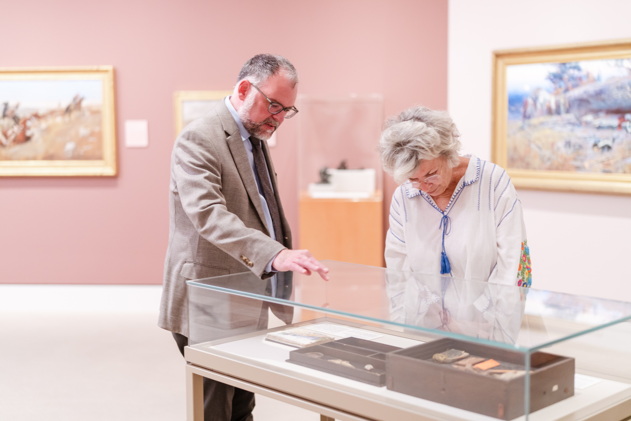 Woman looking at something in glass case at which a man is pointing.