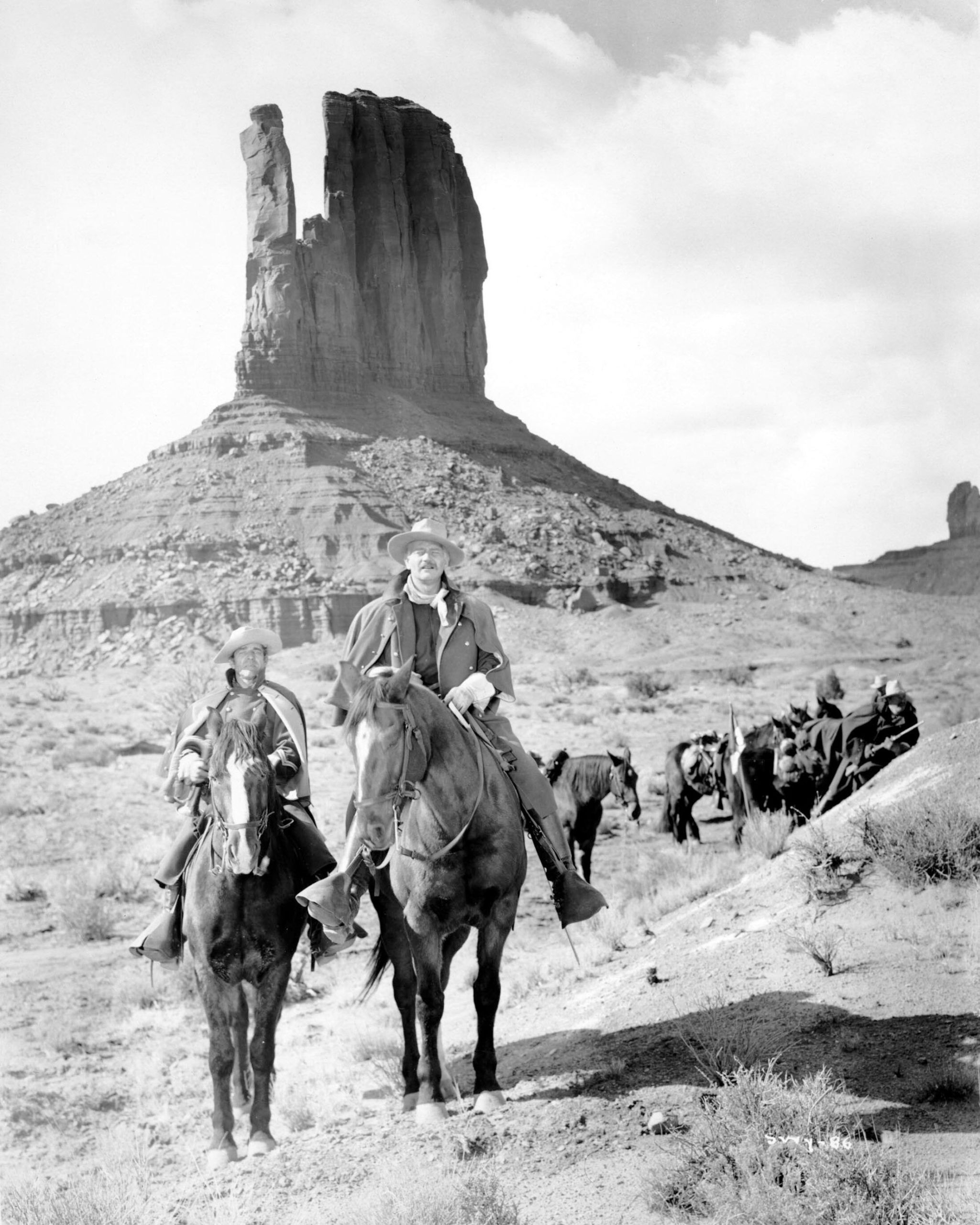 Two men mounted on a horse with Monument Valley in the background