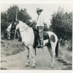 White cowboy posed atop a paint horse.