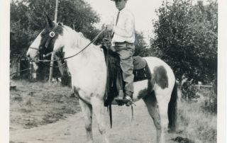 White cowboy posed atop a paint horse.