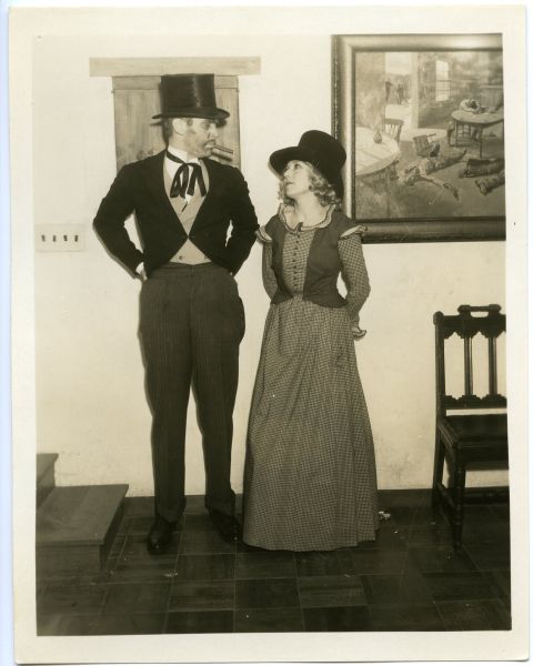 A man and woman dressed up, starring at each other in front of a painting