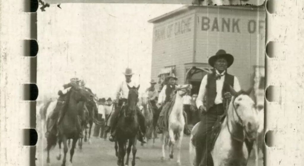 Group of men on horseback strolling down a town road