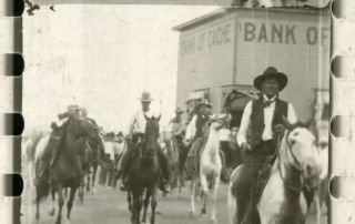 Group of men on horseback strolling down a town road